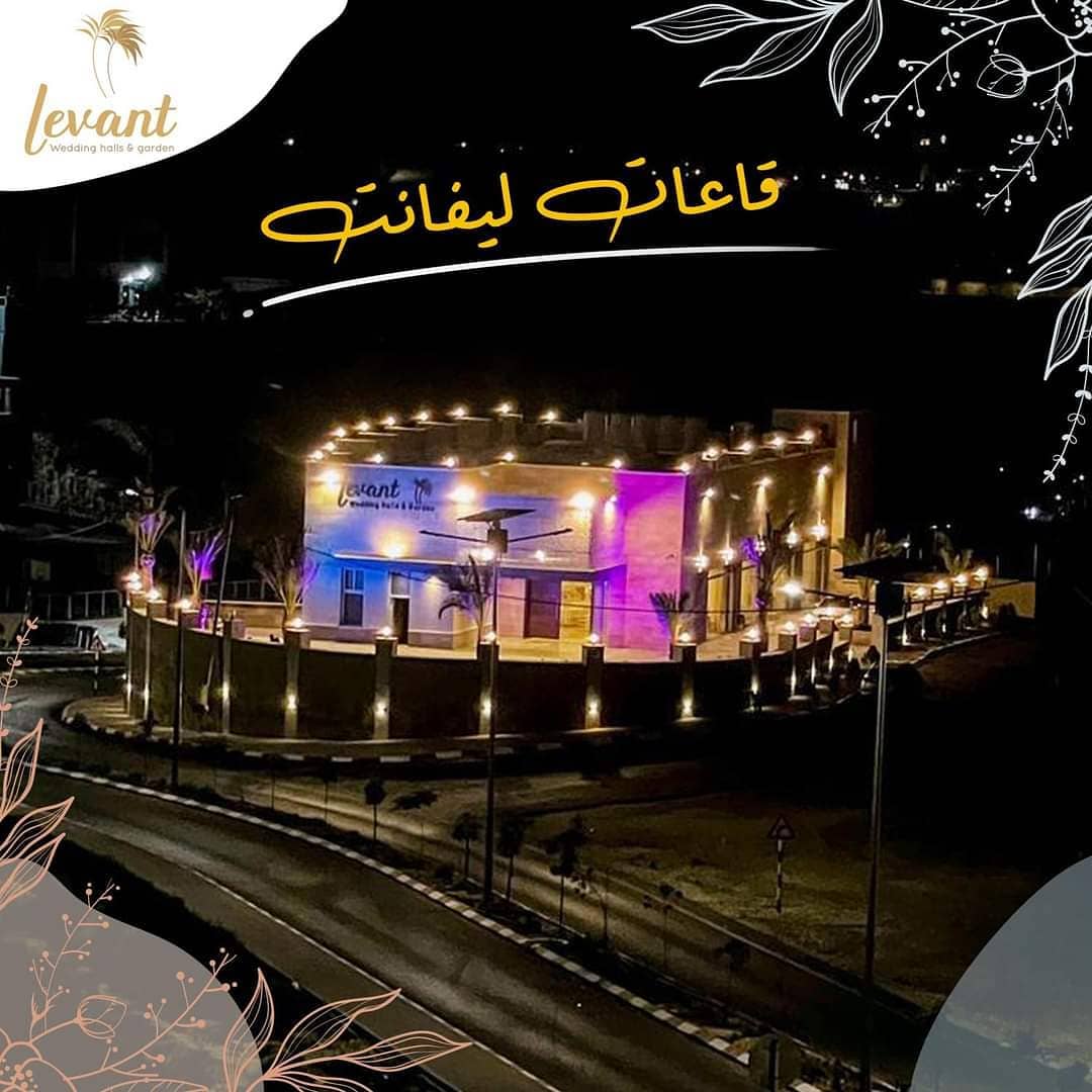 مبنى قاعة ليفانت مضاءً ليلًا مع النخيل والفوانيس على المدخل