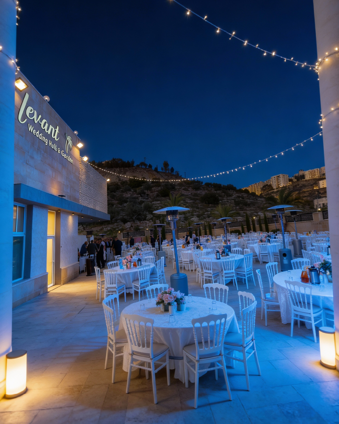الحديقة ليلًا تحت لافتة Levant Wedding Halls and Garden المضاءة مع أضواء معلَّقة